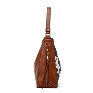 Detail of vintage brown tote bag featuring cow print pattern and gold zipper with tassel