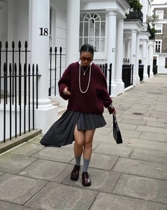 Pull oversize col rond bordeaux tendance porté avec une jupe plissée grise
