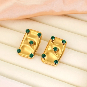 Detail of vintage 18K gold plated earrings with hammered texture and green zircons