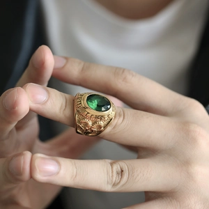 Detalle macro de anillo vintage de oro con piedra verde esmeralda y relieve floral