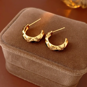 Detailed view of vintage gold hoop earrings with quilted texture and black enamel