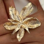 Detail of a large gold floral statement ring featuring textured layered metal petals