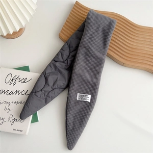 Detail of grey quilted scarf showing waffle texture and creative department label