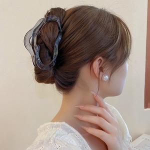 Pince à cheveux ondulée grise transparente élégante pour chignon sur modèle brun