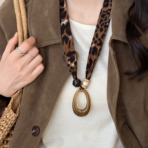 Detail of leopard print fabric necklace with amber resin pendant on a female model