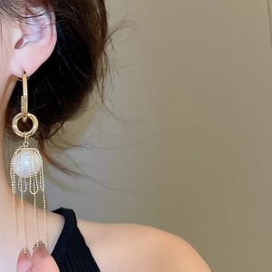 Detail of long gold tassel earrings with pearl and elegant beaded chain fringe design