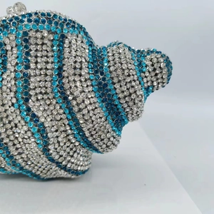 Detail of luxury shell-shaped clutch bag with blue and white sparkling rhinestones