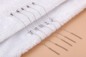 Detailed close-up of initial letter charms F G H I J on polished steel bracelets