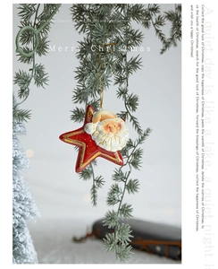 Dettaglio di un ornamento vintage a stella con Babbo Natale appeso a un ramo di pino