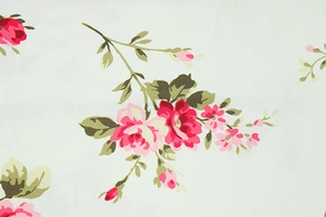 Close-up of pink and red rose floral print on mint green lightweight summer dress fabric
