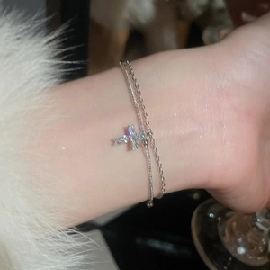 Detail of silver double-layer bracelet featuring a cross charm with sparkling cubic zirconia