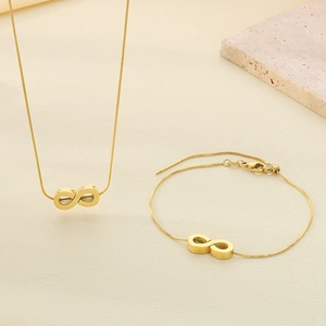 Flat lay view of gold-plated infinity symbol necklace and bracelet set on stone background