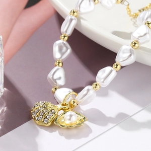 Macro detail of Baroque pearl bracelet featuring rhinestone shell and pearl charm