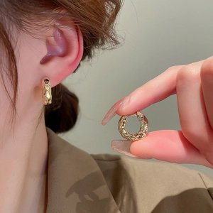 Close-up of golden irregular textured hoop earrings with a metallic hammered finish