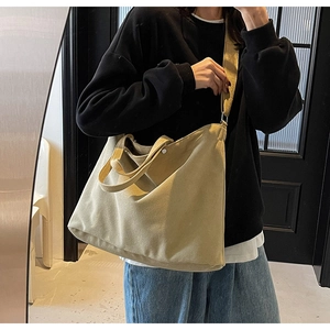 Detailed view of spacious khaki canvas tote bag with wide strap and metallic button detail