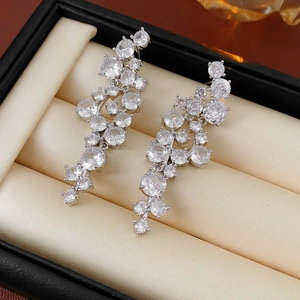 Close-up of irregular silver zircon tassel earrings in a black jewelry box display