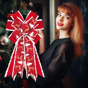 Large red velvet Christmas bow with gold reindeer and white tree patterns on a tree