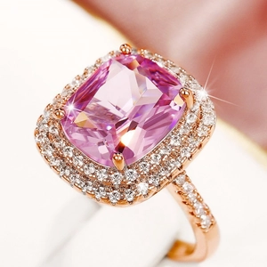 Macro shot of cushion-cut pink gemstone ring with halo diamonds on rose gold band
