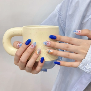 Handmade ocean blue press-on nails with star patterns on a model holding a mug