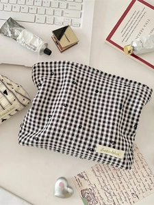 Checkered heart makeup bag in black and white with floral embroidery on the desk