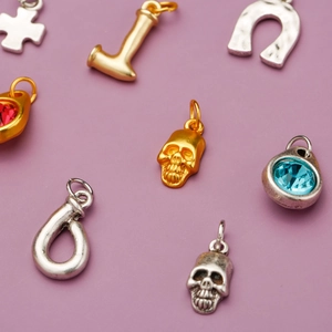 Assorted alloy charms featuring skulls, crosses, and gemstones on a purple backdrop