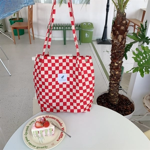 Red and white checkerboard corduroy tote bag hanging in a cozy cafe setting