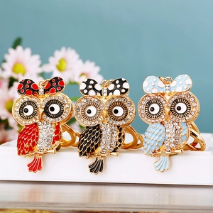 Detailed macro view of rhinestone-encrusted owl keychains in red, black, and blue finishes