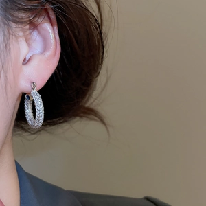 Macro side view of silver hoop earrings with pavé set cubic zirconia on earlobe