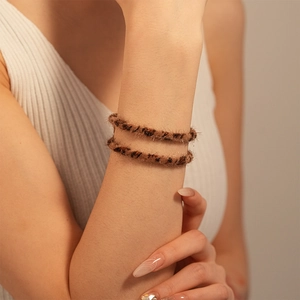 Close-up of leopard print plush hair ties and bracelets worn on a model's wrist