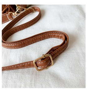 Close-up of brown PU leather adjustable shoulder strap with gold buckle and white stitching
