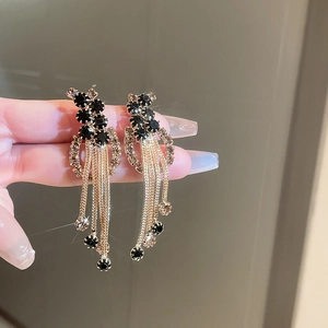 Gros plan de boucles d'oreilles dorées à franges avec strass noirs et pompons