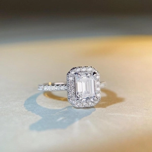Elegant emerald cut silver ring with halo diamonds and side stones on a matte base
