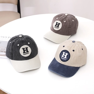 Detailed view of three washed cotton baseball caps with Happy letter patches on a table