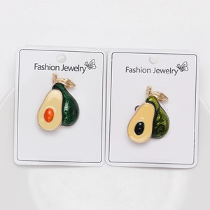 Close-up of two cute avocado brooches with orange and black pits on display card