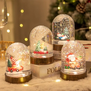 Christmas snow globe lanterns with Santa and snowman on a warm glowing wooden base