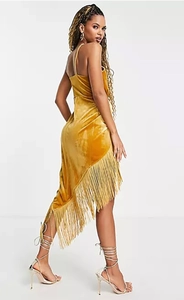 Détail d'une robe en velours jaune gingembre avec ourlet asymétrique et franges élégantes