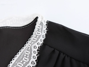 Detail of the V-neckline featuring intricate white lace trim on a black chiffon dress