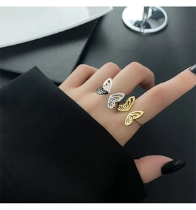 Detailed view of layered hollow butterfly rings in gold and silver on a model