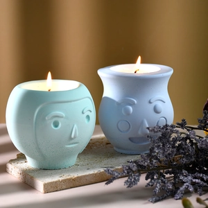 Dettaglio di candele profumate a forma di viso accese su pietra con fiori secchi