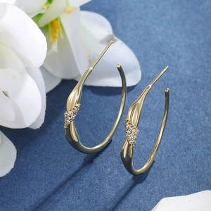 Macro detail of gold-plated teardrop earrings with sparkling cubic zirconia on blue fabric