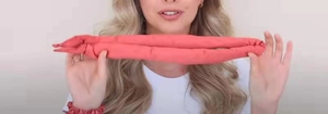 Detailed view of a soft red heatless hair curler and matching scrunchie on a wrist