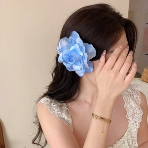 Close-up detail of a large blue gradient silk rose flower hair clip worn on a model's hair.