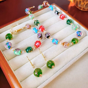 Close-up of colorful floral glass beads jewelry set with gold foil in a velvet display box