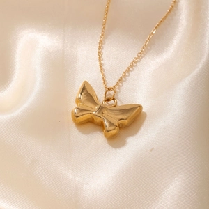 Polished gold butterfly pendant necklace on elegant champagne satin fabric background