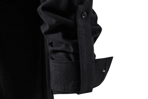 Detail van de verstelbare knoopmanchet op een zwart katoenen linnen shirt met lange mouwen
