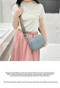 Close-up of grey-blue cross-body bag with lychee texture and wide striped fabric strap