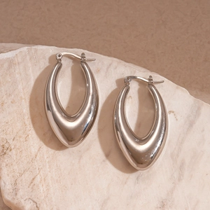 Detailed macro view of silver water drop hoop earrings on a textured stone base