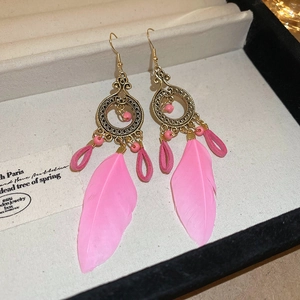 Bohemian-Ohrringe mit rosa Federn, goldenen Haken und Perlen in einer Schmuckschatulle