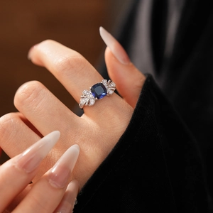 Vue macro d'une bague en argent avec pierre carrée bleue et petits diamants sur le doigt