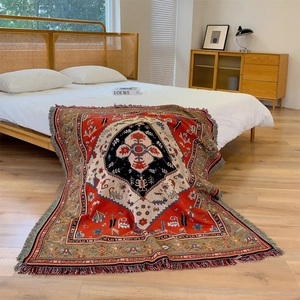 Couverture de camping bohème avec motifs tribaux et franges, drapée sur lit et sol